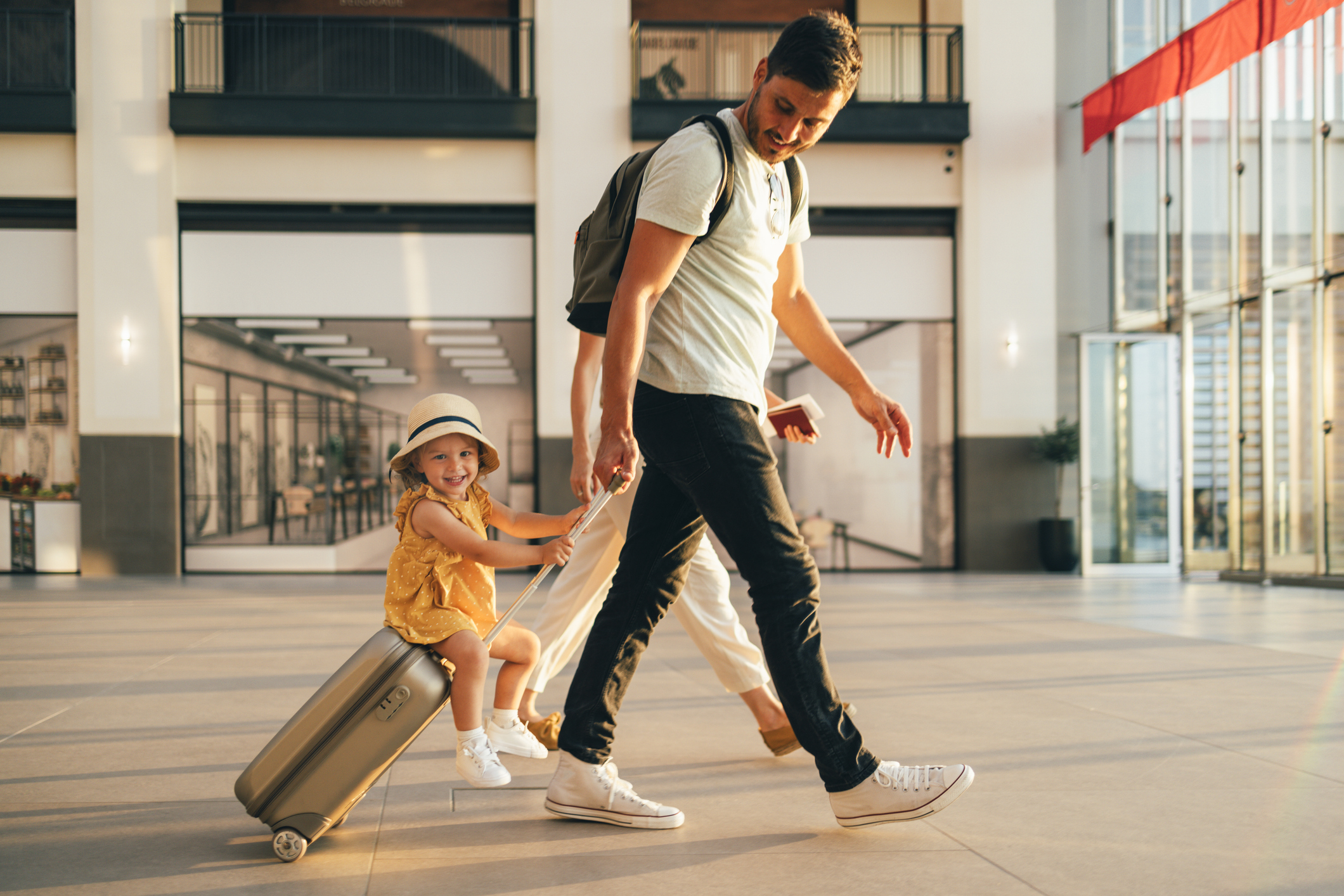 Kind auf Koffer wird von Vater gezogen